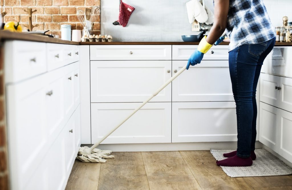 A person who's selling their home during the holidays mopping up the kitchen floor. 